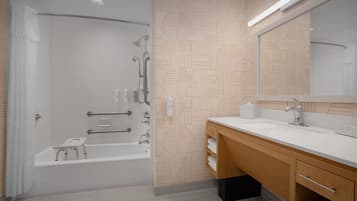 A modern bathroom with a bathtub, shower, and vanity with a mirror.