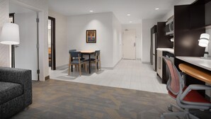 A modern hotel room with a dining area, a sofa, a desk, and a chair.