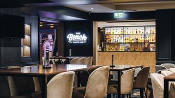 Eine Bar mit einer Neonreklame, einer Spirituosenpräsentation und Sitzmöglichkeiten.