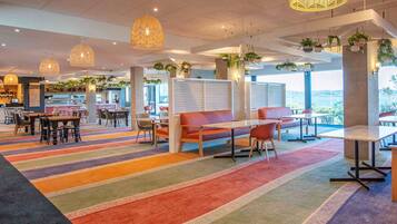 A modern indoor space with striped carpeting, seating areas, and hanging plants.