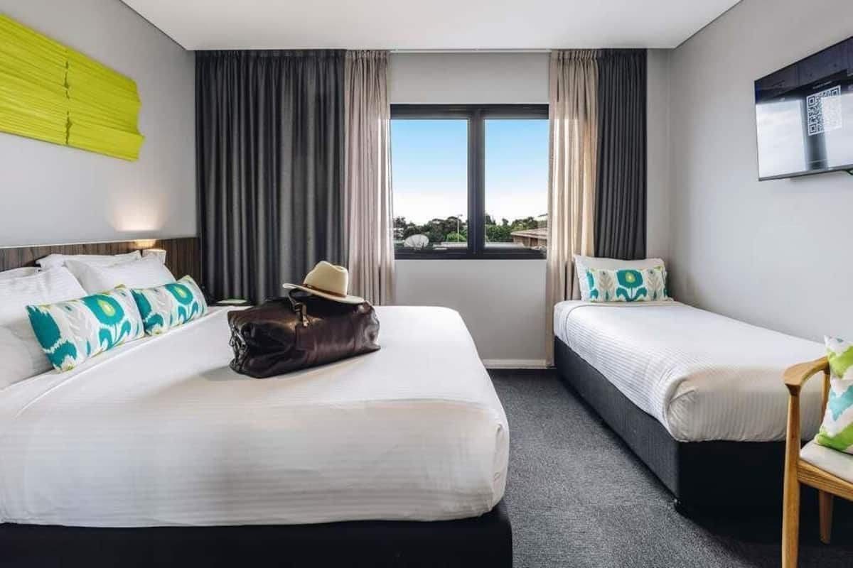 Habitación de hotel con dos camas, un ventanal grande, televisor de pantalla plana y vistas al exterior.
