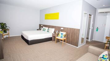 Een hotelkamer met een groot bed, een houten nachtkastje, een stoel en een bank.