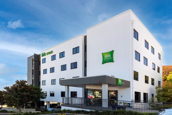 Un hotel moderno con fachada plana, varias ventanas y un llamativo letrero verde 'ibis styles'.