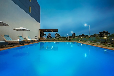 Una piscina al aire libre, sombrillas, sillones reclinables de piscina