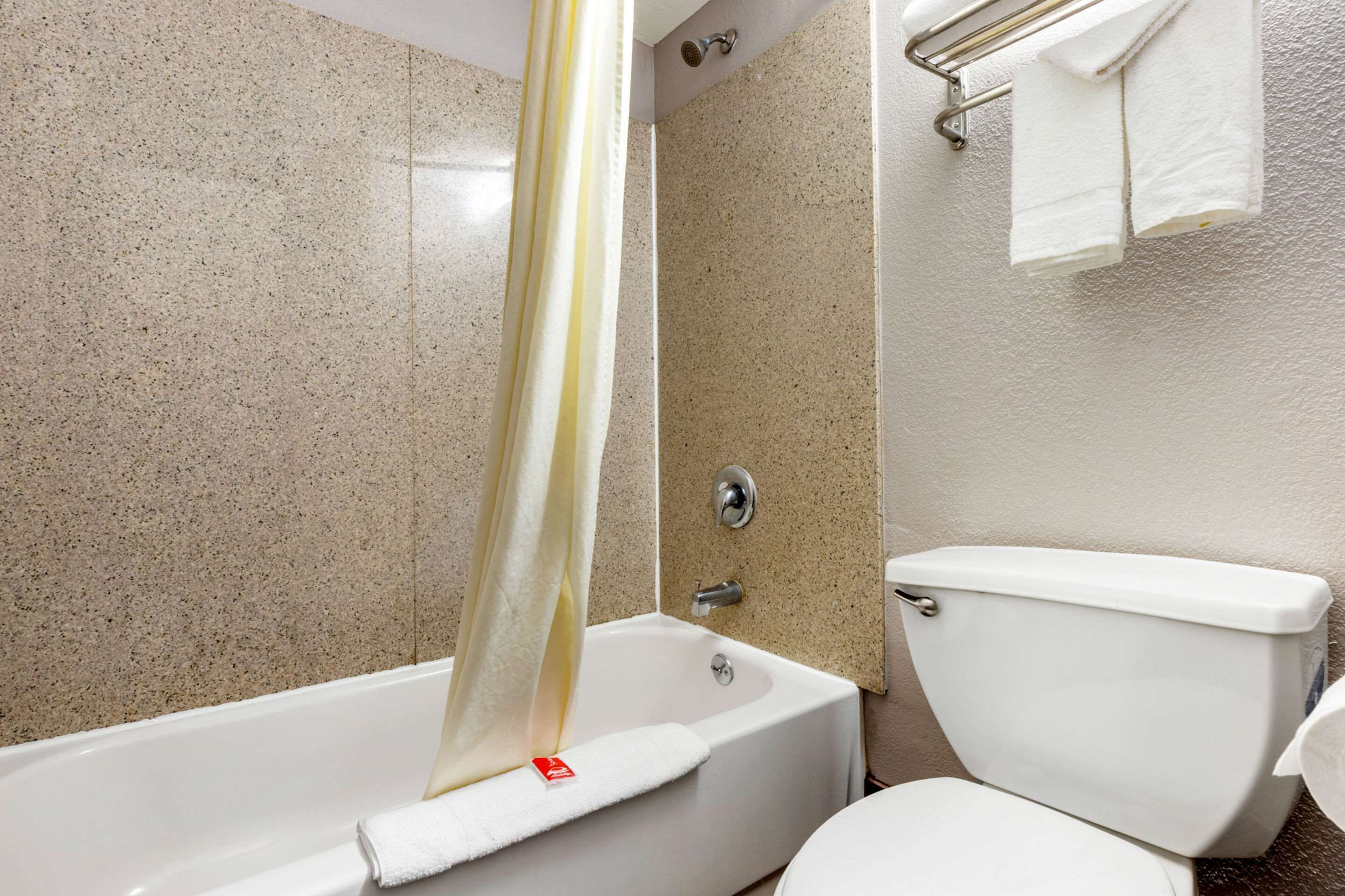 Un baño con bañera, inodoro y toallero.