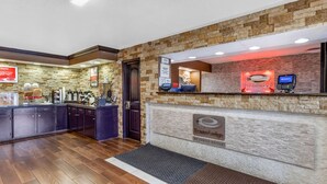 Un área de recepción con pared de piedra, mostrador de recepción, cafetera y teléfono.