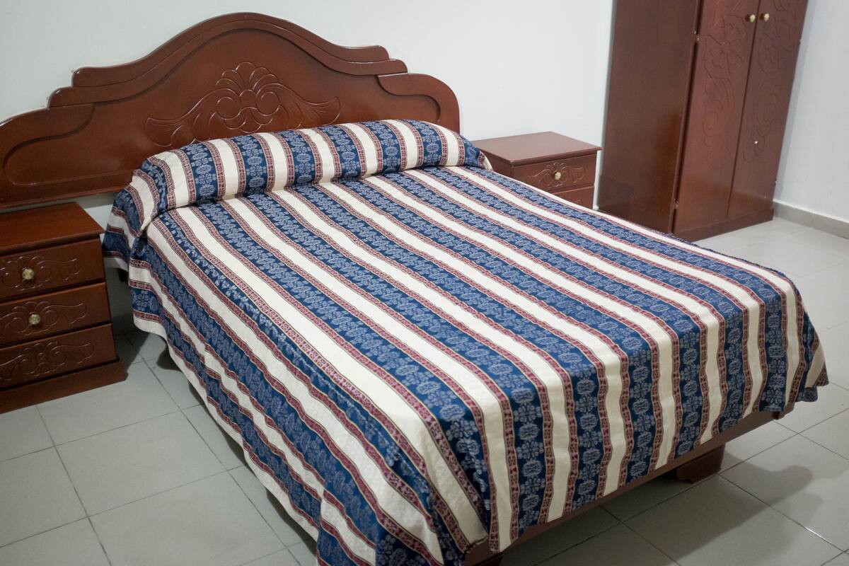 A bedroom with a wooden bed, a nightstand, a wardrobe, and a dresser.
