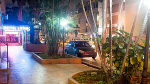 Entrada de un hotel con un letrero de neón, un camino pavimentado y un automóvil estacionado cerca.