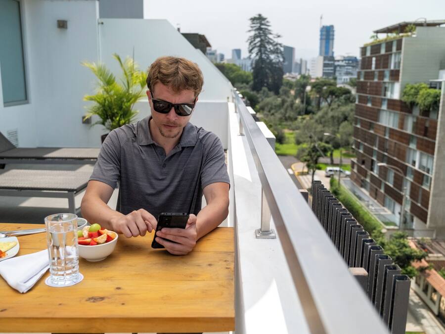Un hombre sentado a una mesa con un tazón de fruta, un vaso de agua y un plato de comida.