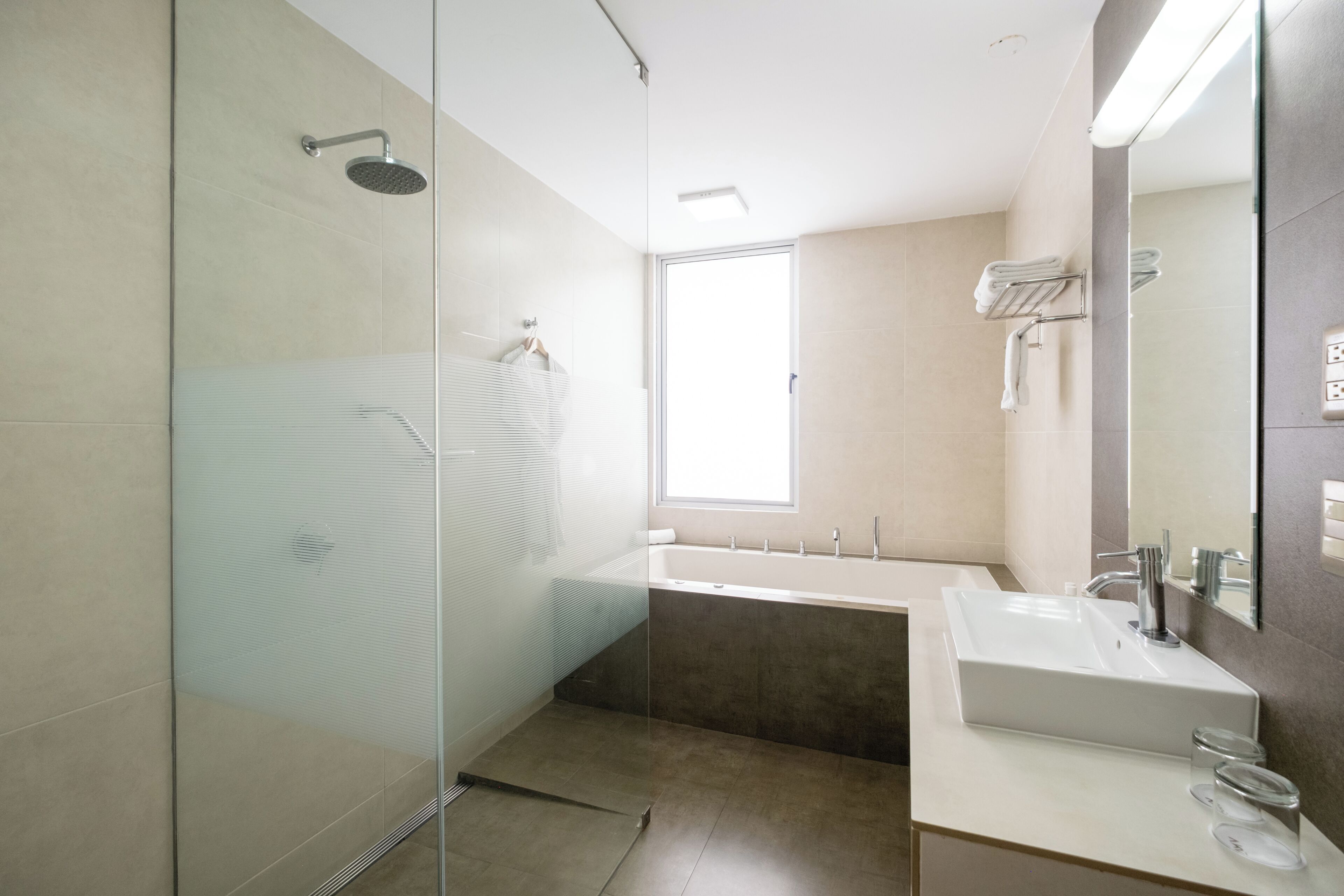 Ein modernes Badezimmer mit Duschkabine aus Glas, einer Badewanne und einem weißen Waschtisch mit Spiegel.