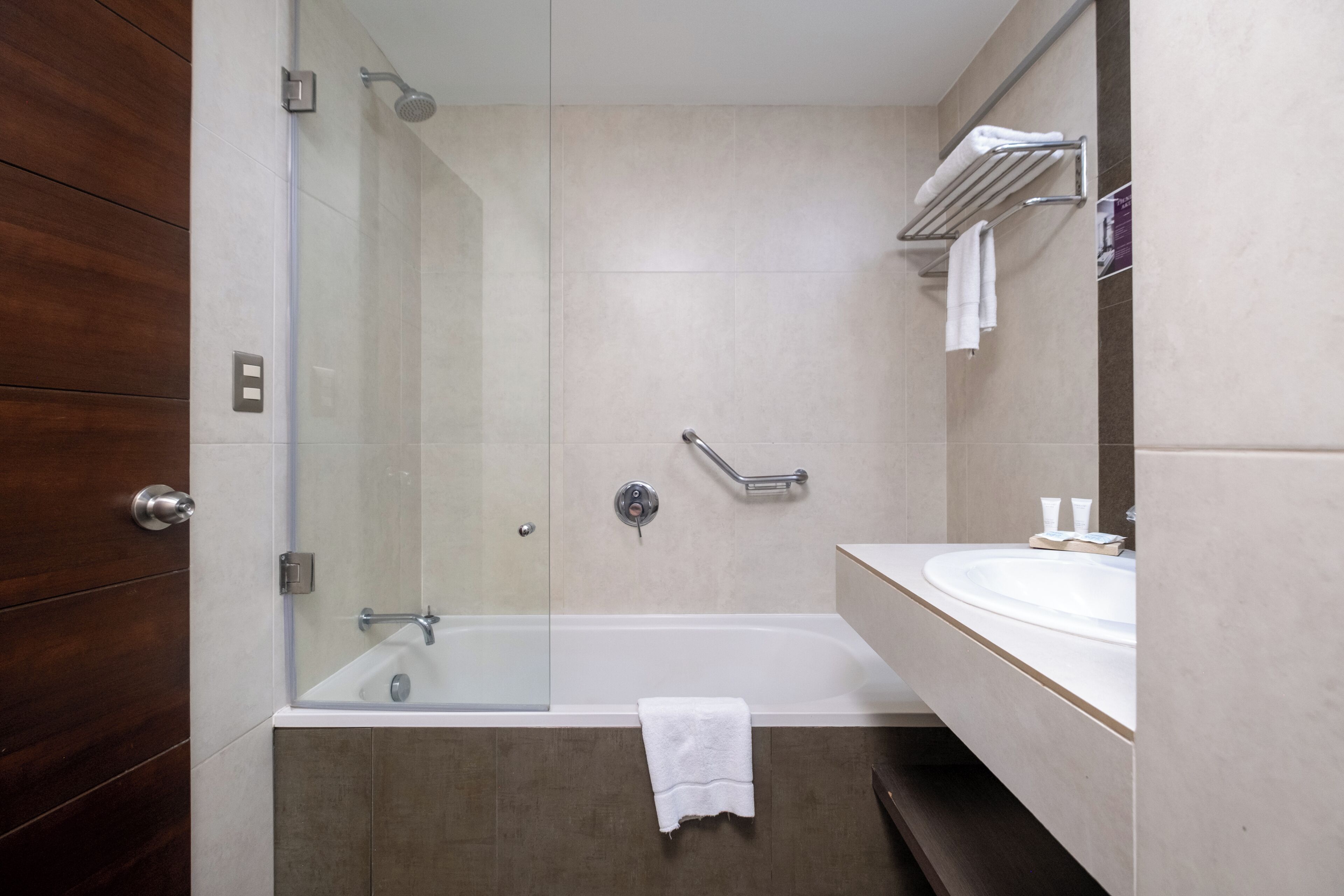 A modern bathroom with a glass-enclosed shower, a bathtub, and a vanity with a mirror.