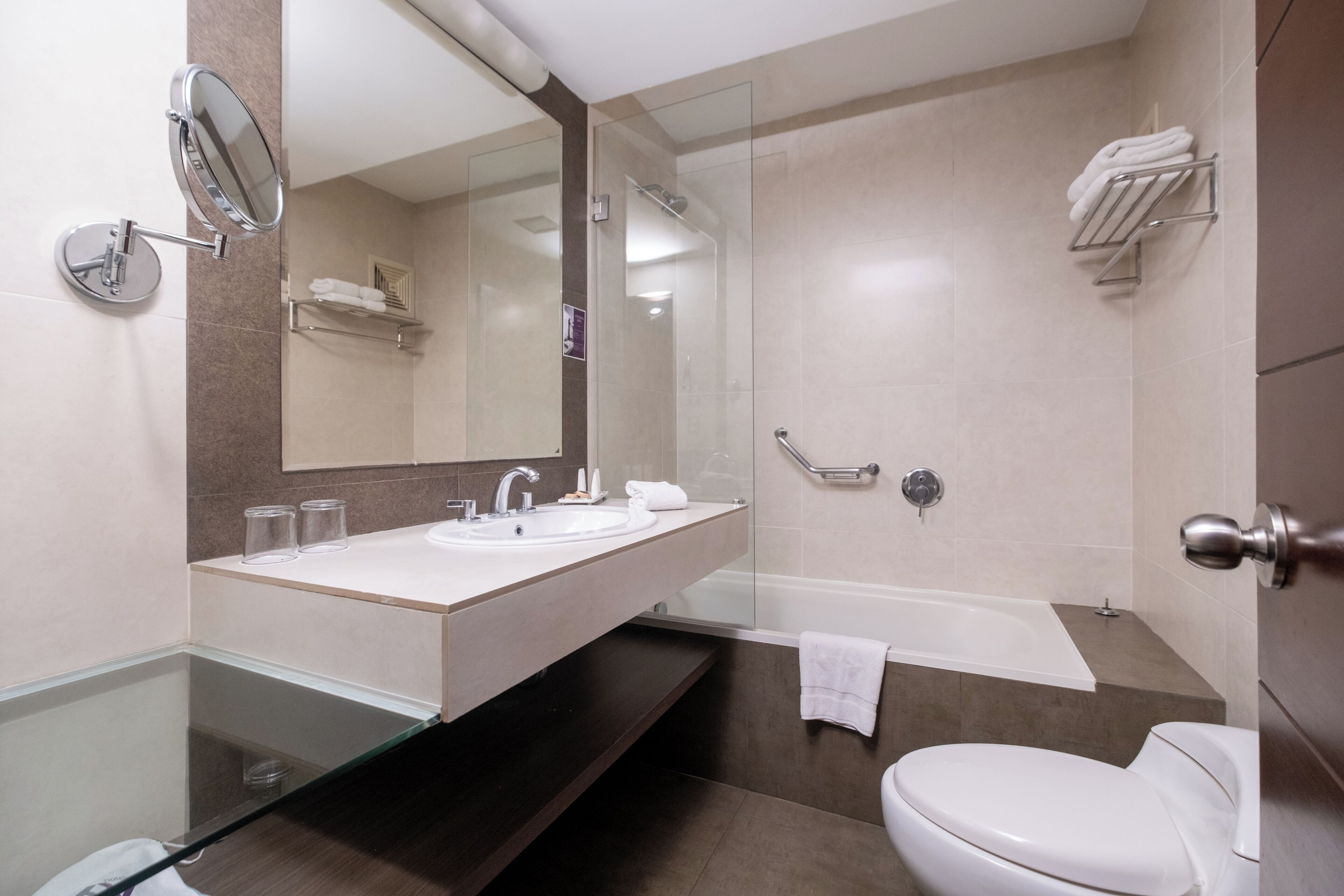Un baño moderno con cabina de ducha de vidrio, bañera, inodoro y tocador con lavamanos.