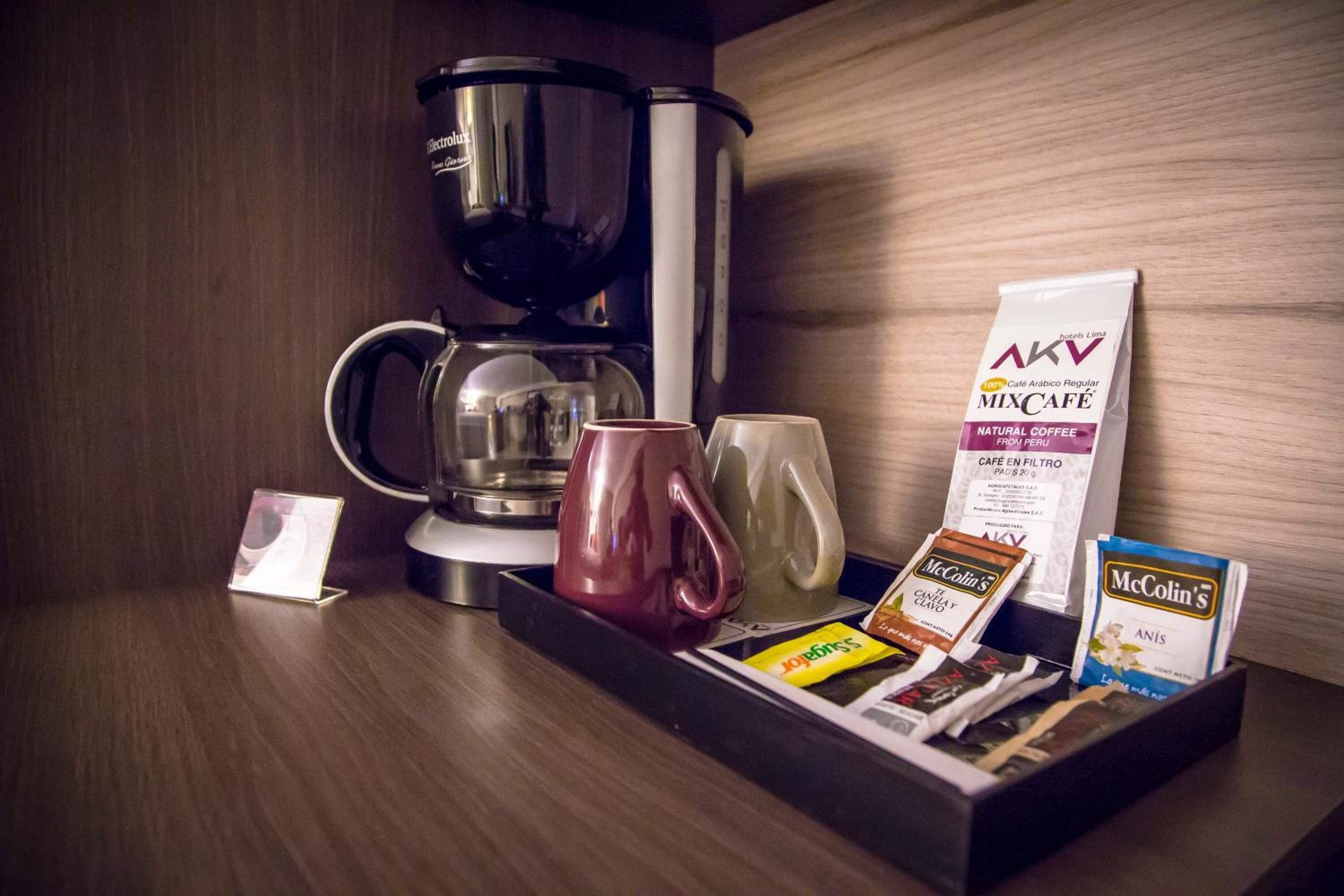 Un coin café équipé d’une machine à café, de tasses et de sachets de café.