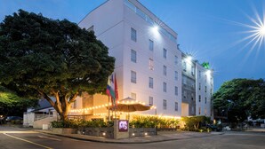 A multi-story hotel with a well-lit entrance, a flag, and a sign indicating it is a Marriott hotel. - Hotel MS Ciudad Jardín Plus (Cali)
