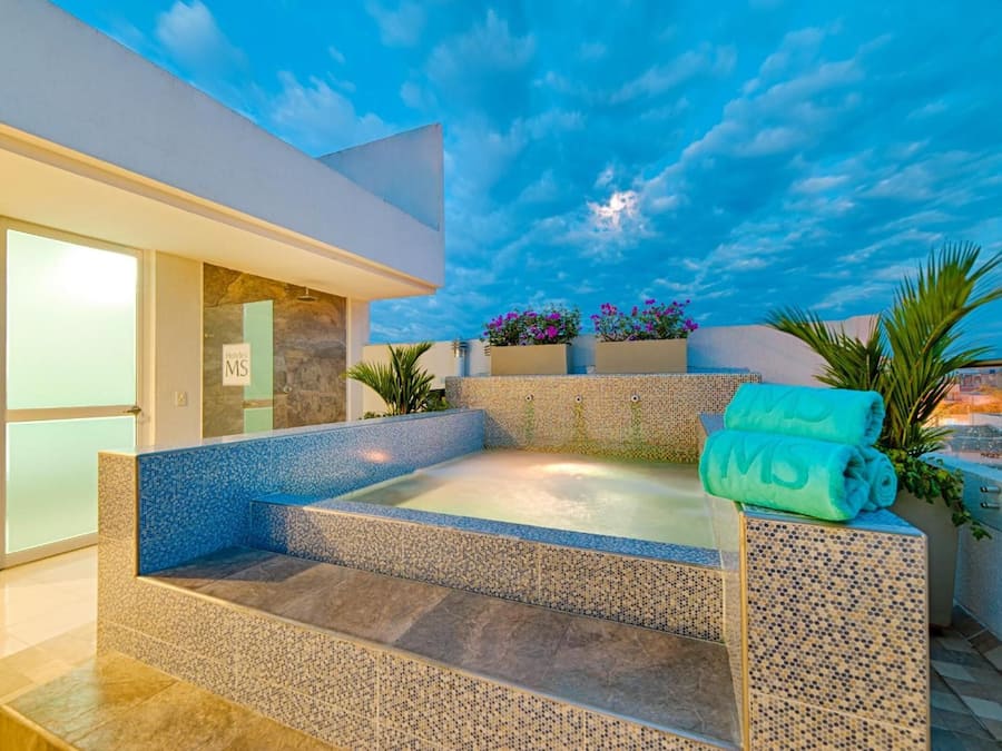 Un área de spa con un jacuzzi, escalones que lo llevan y vistas al cielo.