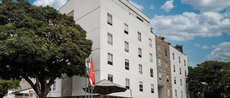 Un hotel de varios pisos con fachada blanca, amplias ventanas y una bandera.