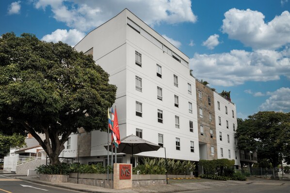 A multi-story hotel with a white facade, large windows, and a flag.