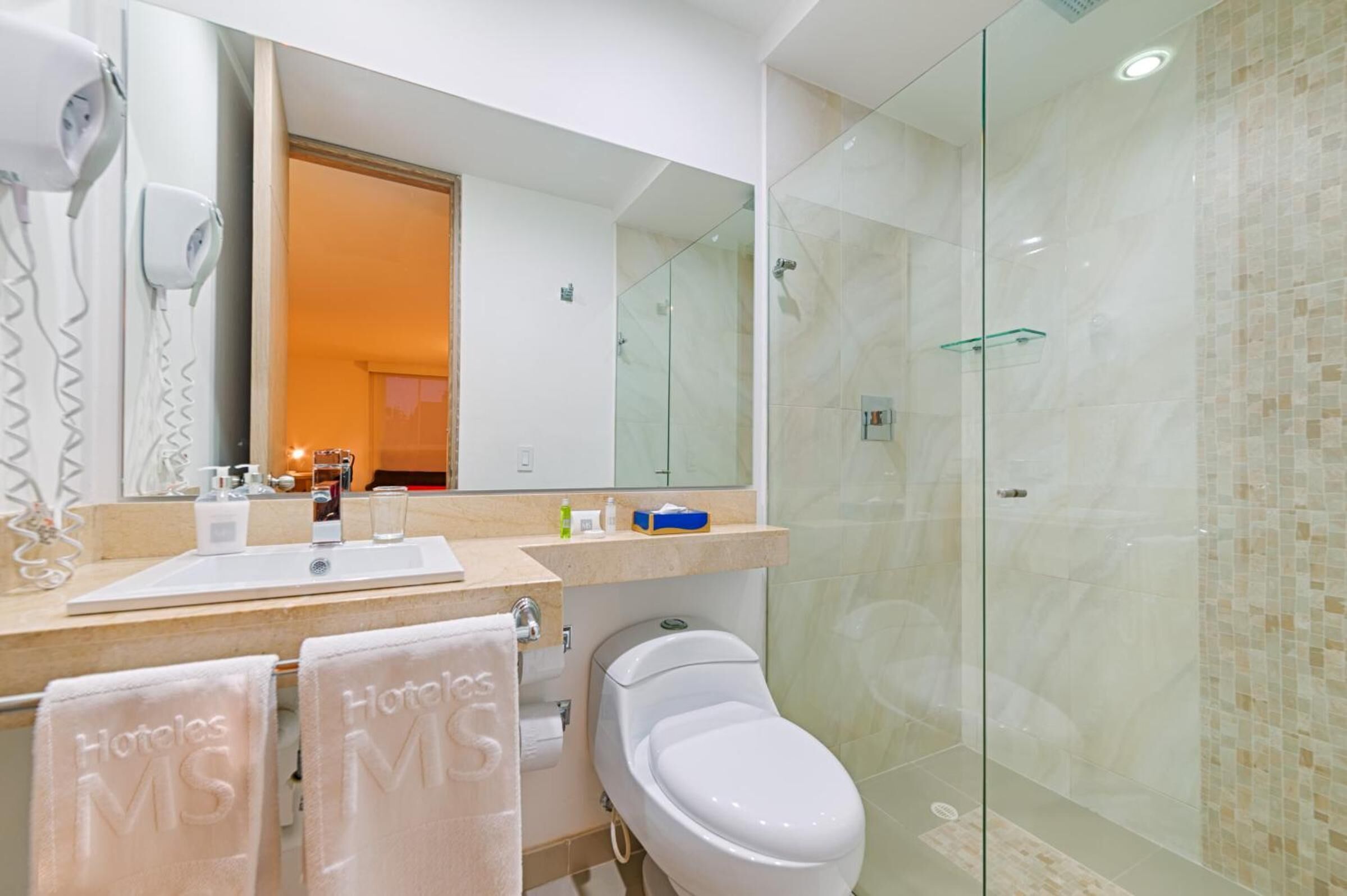 A modern bathroom with a glass shower enclosure, a large mirror, and a vanity with toiletries.