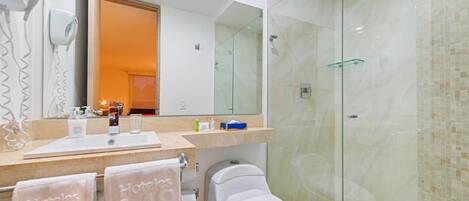 A modern bathroom with a glass shower enclosure, a large mirror, and a vanity with toiletries.