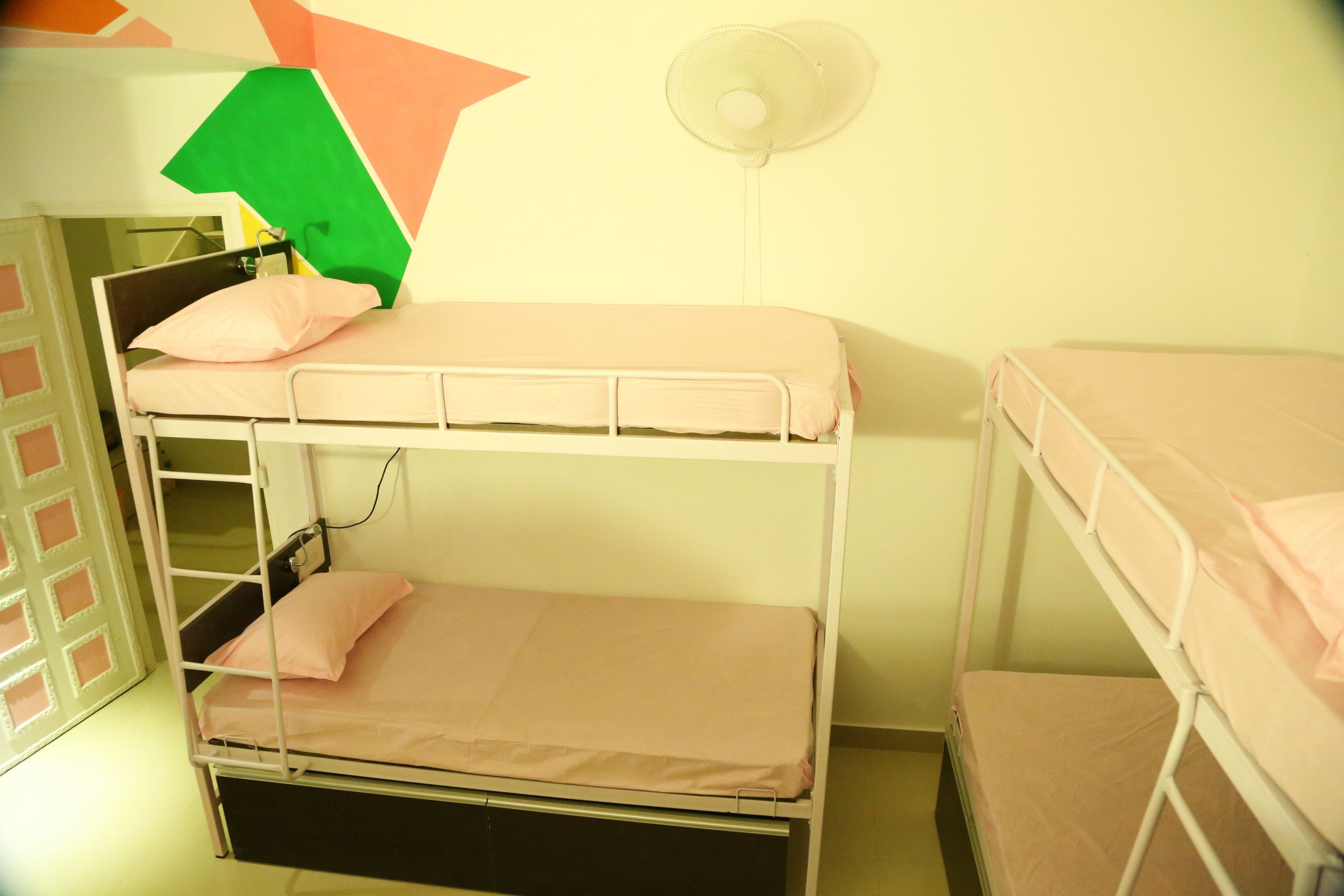 A bunk bed room with a fan and a green object on the wall.