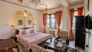 Una habitación de hotel con una cama, un sofá, una mesa con hervidor y un televisor.