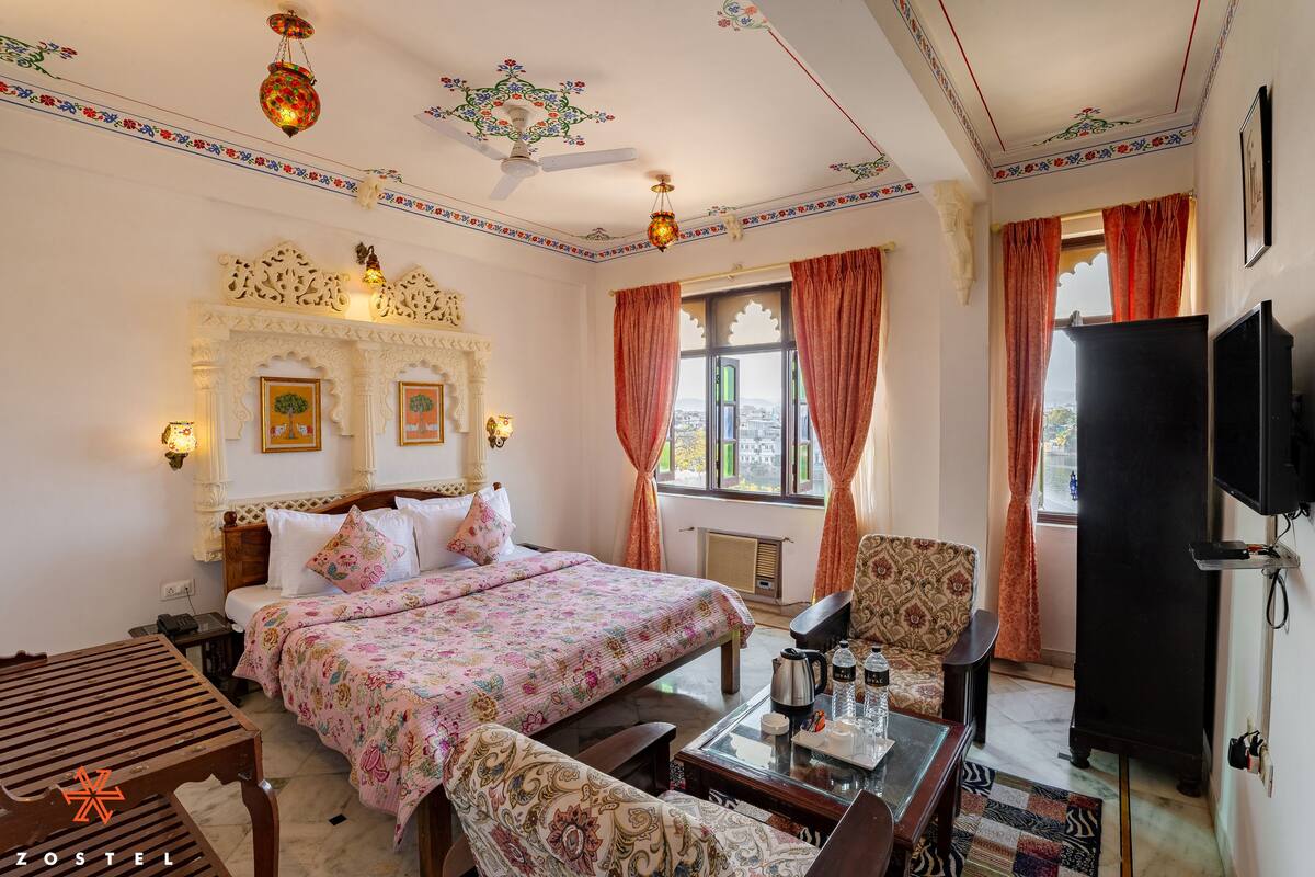 Une chambre d’hôtel comprenant un lit, un canapé, une table avec une bouilloire et un téléviseur.