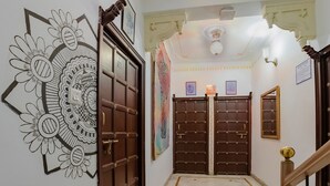 Un pasillo con dos puertas de madera, un adorno en la pared, un ventilador de techo y un cartel que indica 'Quiet Hours'.