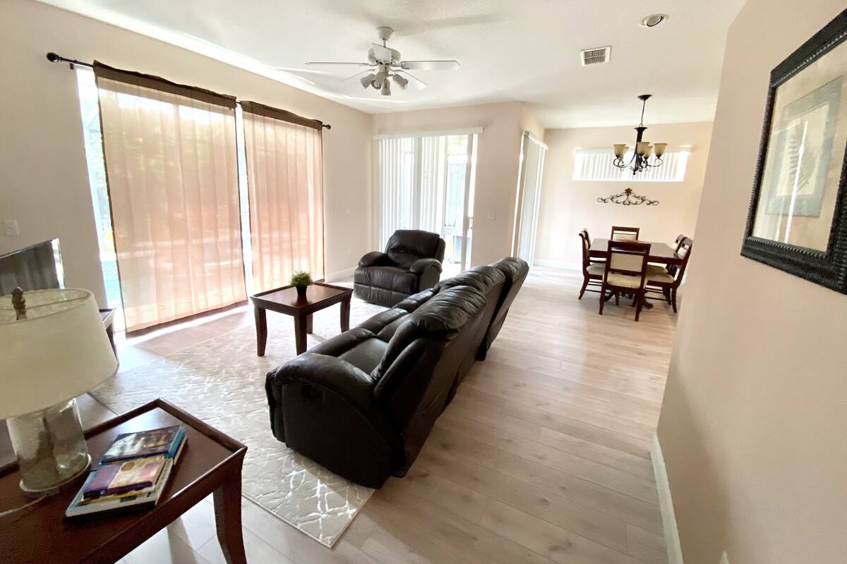 Uma sala de estar ampla com sofá, mesa de centro e área de jantar com cadeiras e mesa.