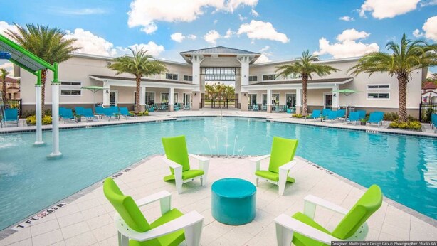 A pool area with a central fountain, surrounded by lounge chairs and palm trees. - Orlando Select Vacation Homes (Kissimmee)