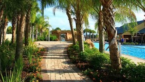 A pathway leading to a pool area surrounded by palm trees and greenery. - Paradise Palms Resort Orlando (Kissimmee)