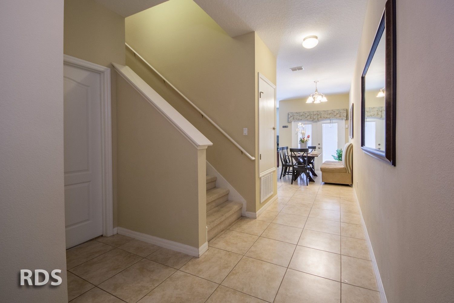 A hallway with a staircase leading to a dining area.