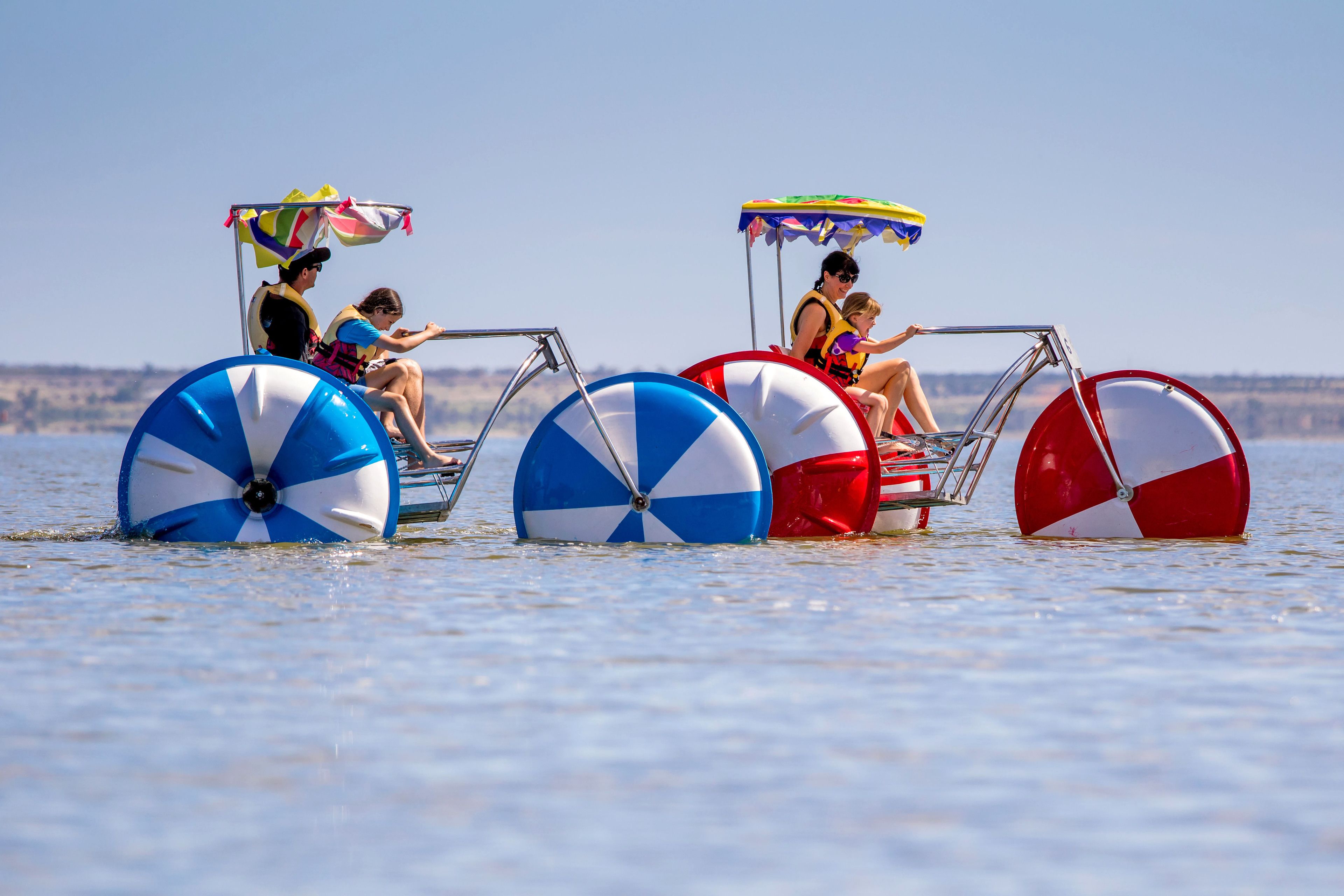 A watercraft with large beach umbrellas and people on board.