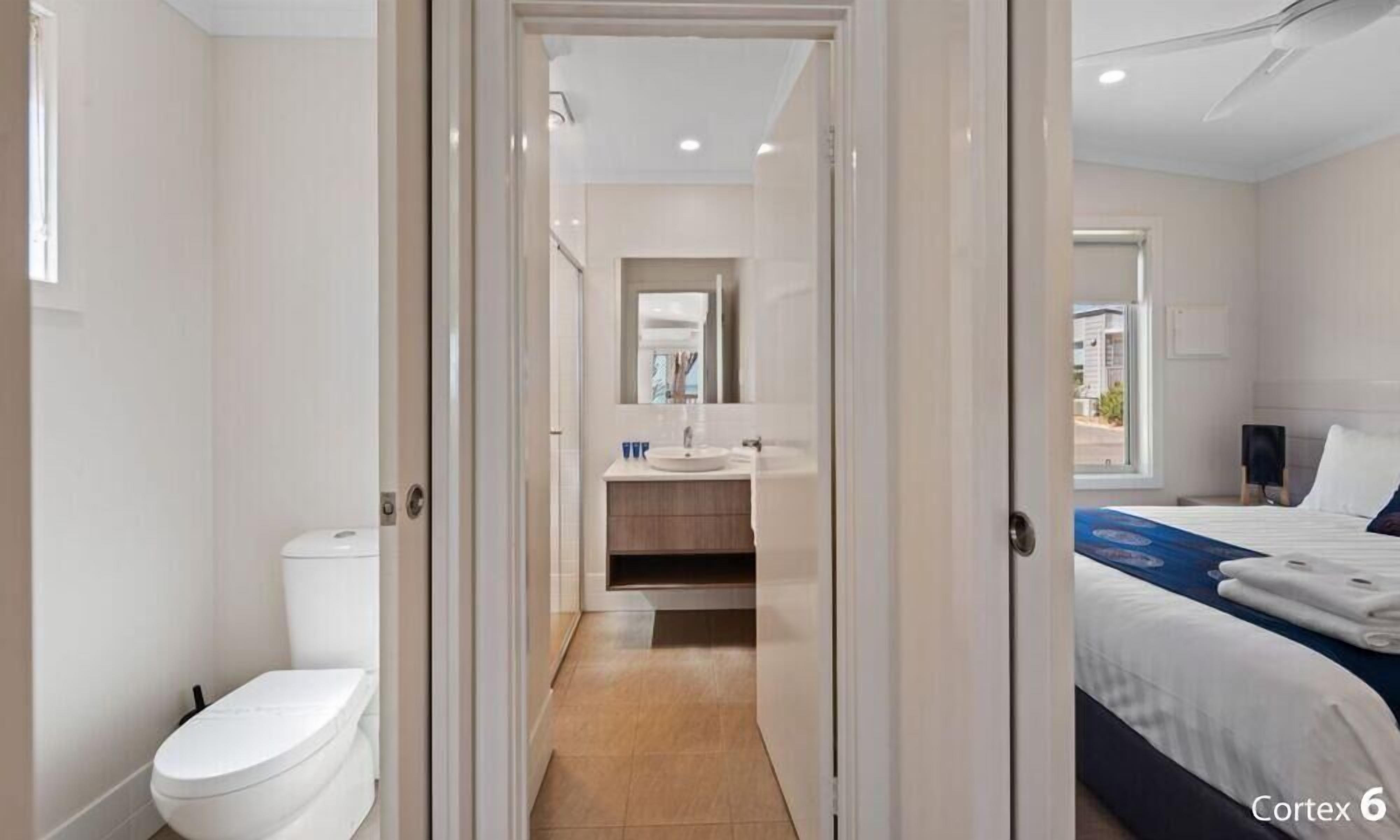 A modern hotel room with a bathroom, a bed, and a view of the outside.