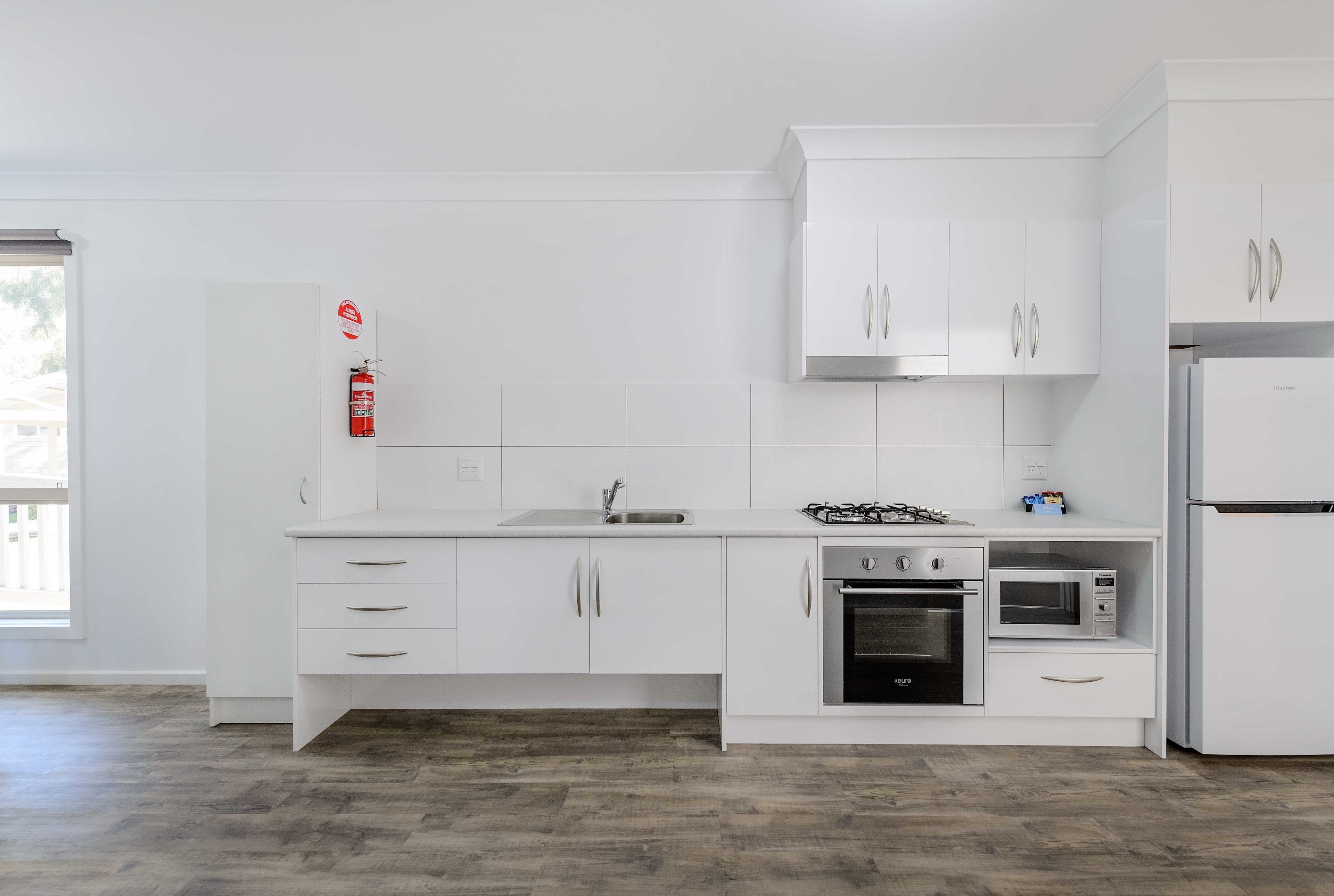 Una cocina moderna con armarios blancos, estufa a gas, horno y microondas.