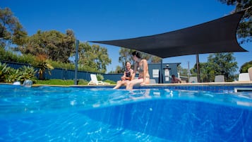 Una piscina al aire libre, sillones reclinables de piscina