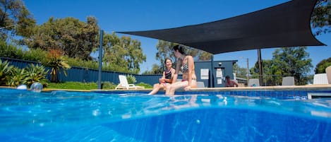 Una piscina al aire libre, sillones reclinables de piscina