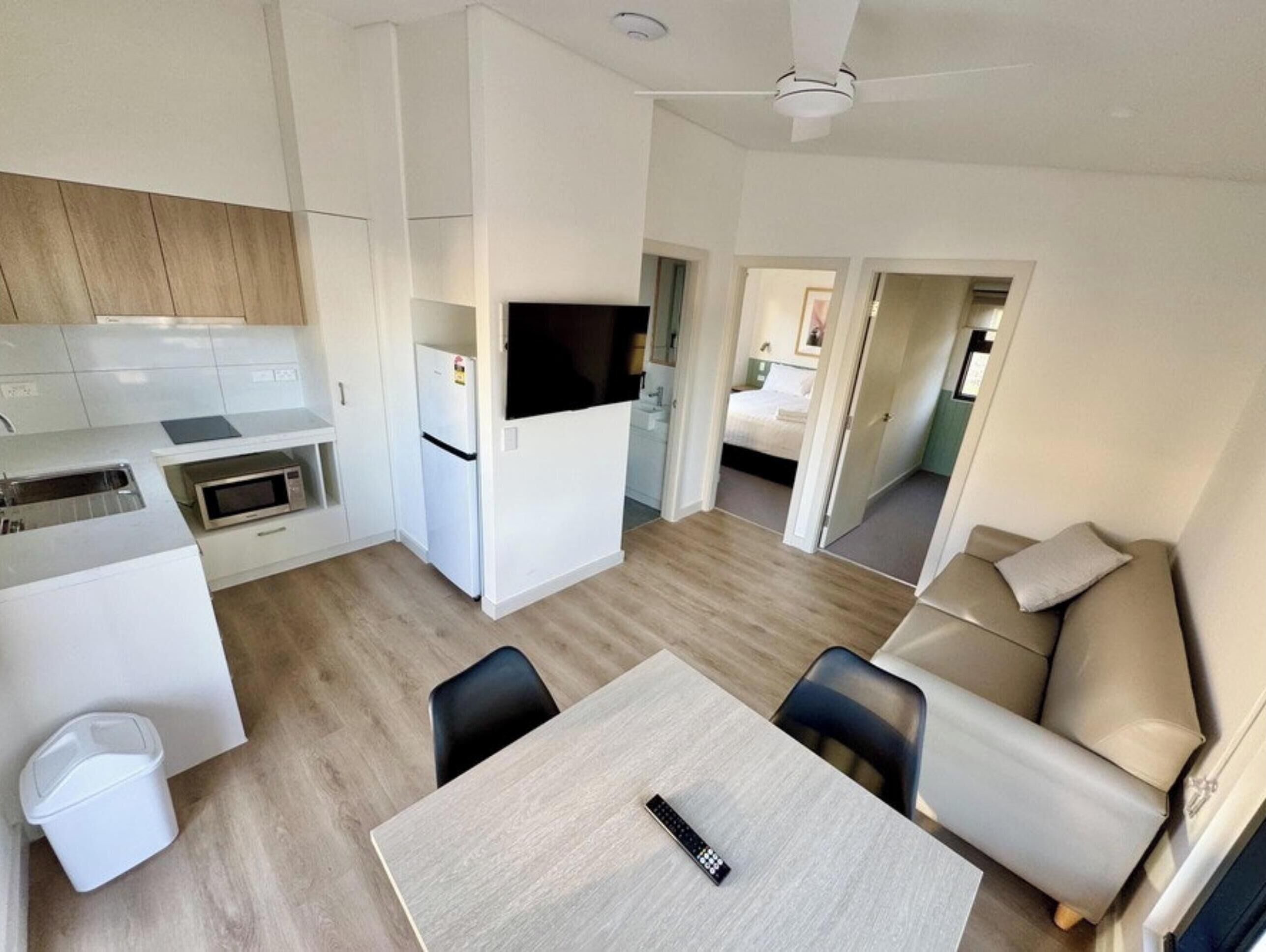 A compact living space with a kitchenette, a dining area, and a bedroom.