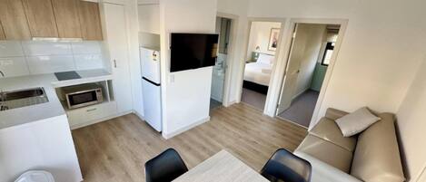 A compact living space with a kitchenette, a dining area, and a bedroom.