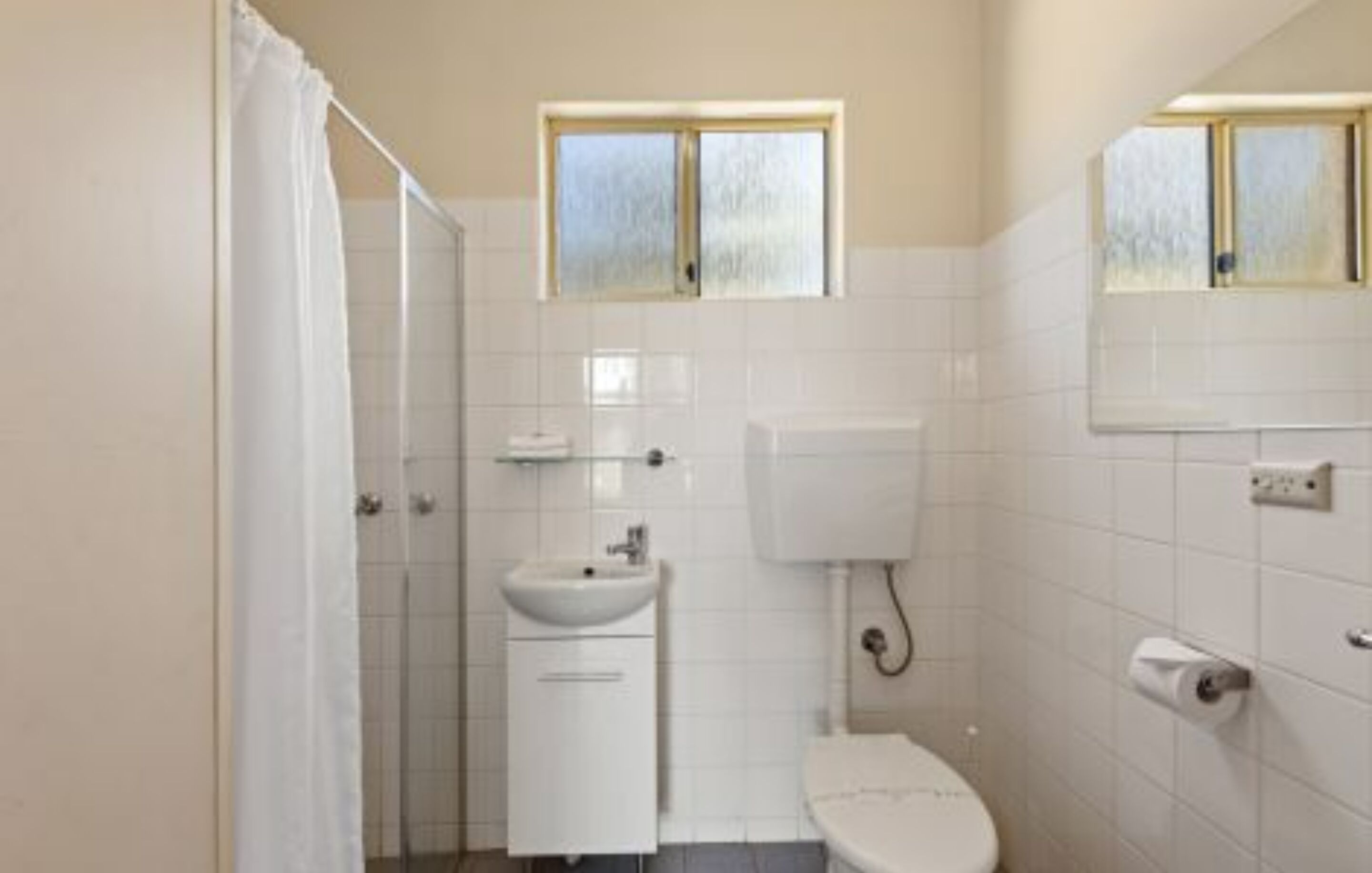A bathroom with a toilet, sink, and shower area.
