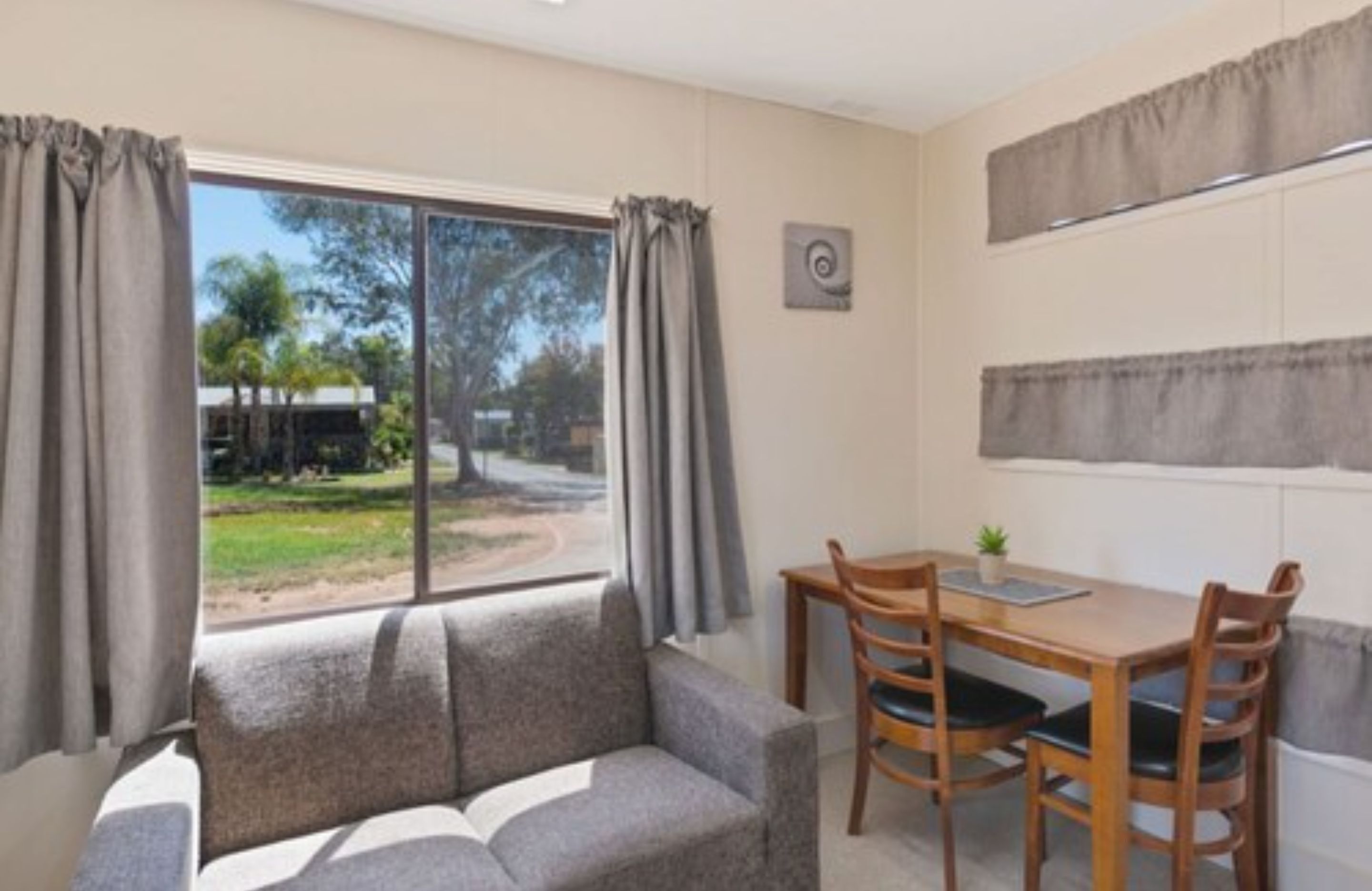 Una habitación con sofá, una mesa de comedor con sillas y una ventana con cortinas.