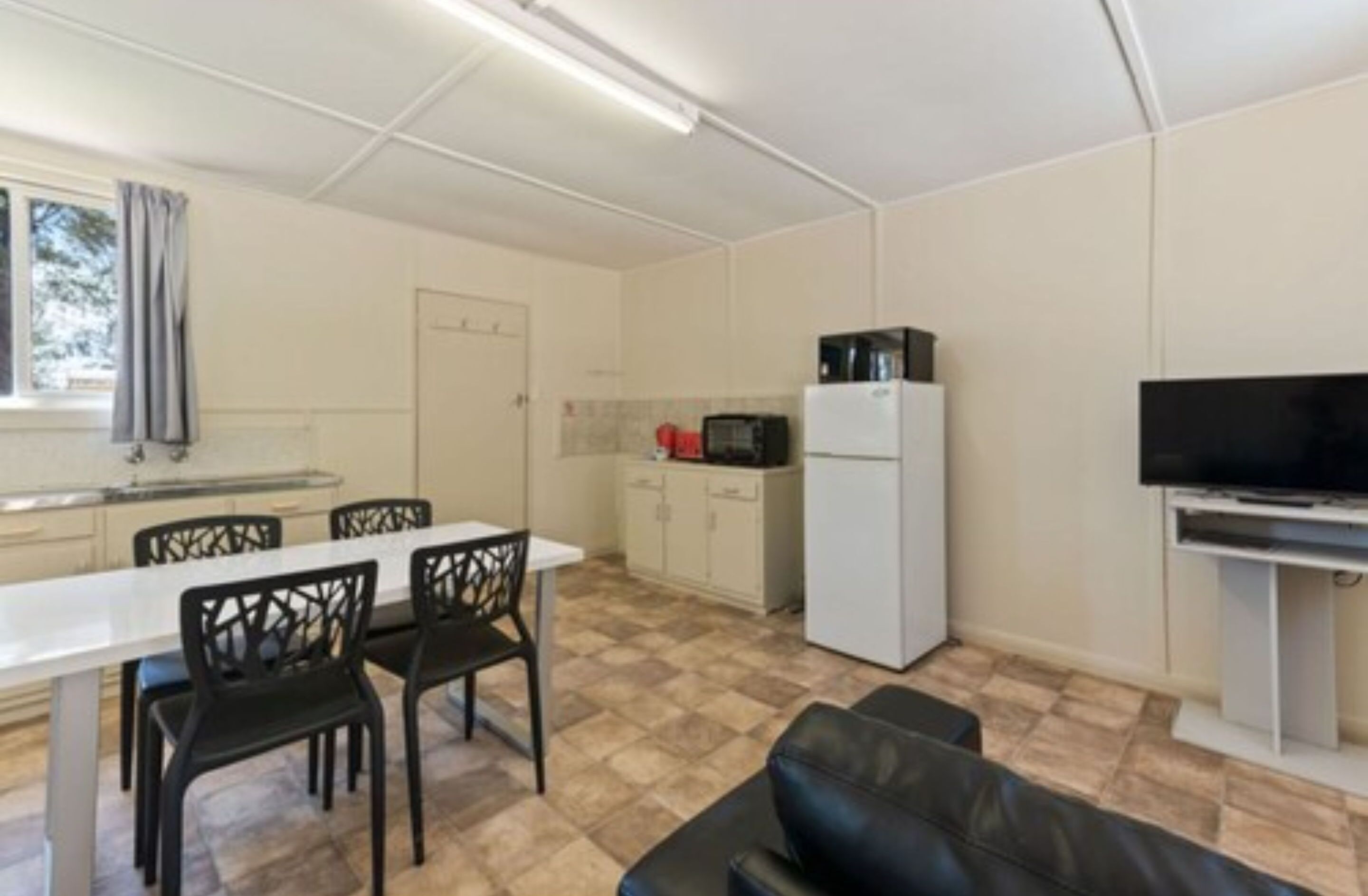 A compact living space with a kitchenette, dining area, and a seating area with a sofa.