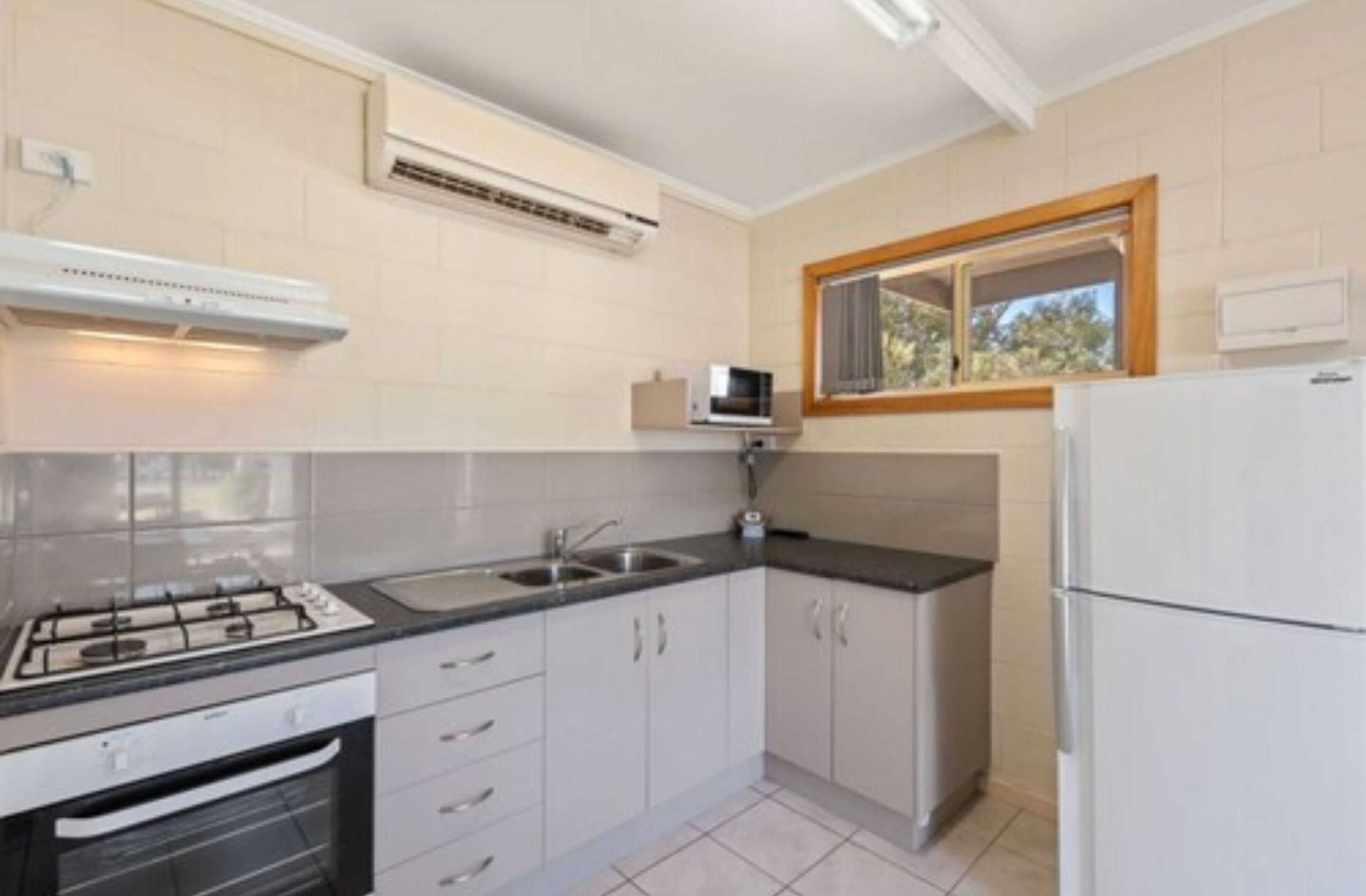 A kitchen with white cabinets, a gas stove, a microwave, and a refrigerator.