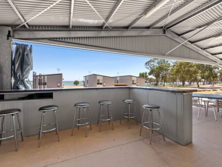 An outdoor bar area with a metal roof, a counter, and four stools.