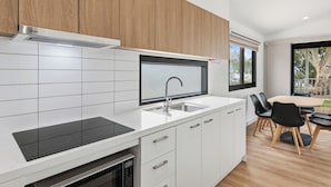 Una cocina moderna con armarios blancos, una placa de inducción negra y un lavamanos integrado.