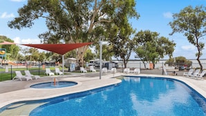 Piscina con sillas de descanso y zona sombreada.