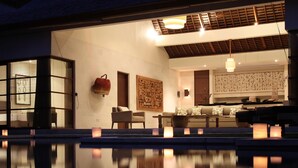 A modern hotel interior with a pool, seating area, and decorative wall art. - Nyaman Villas (Seminyak)
