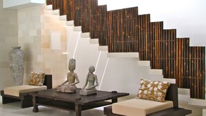 A modern interior with a staircase, two sofas with cushions, and a decorative vase. - Nyaman Villas (Seminyak)