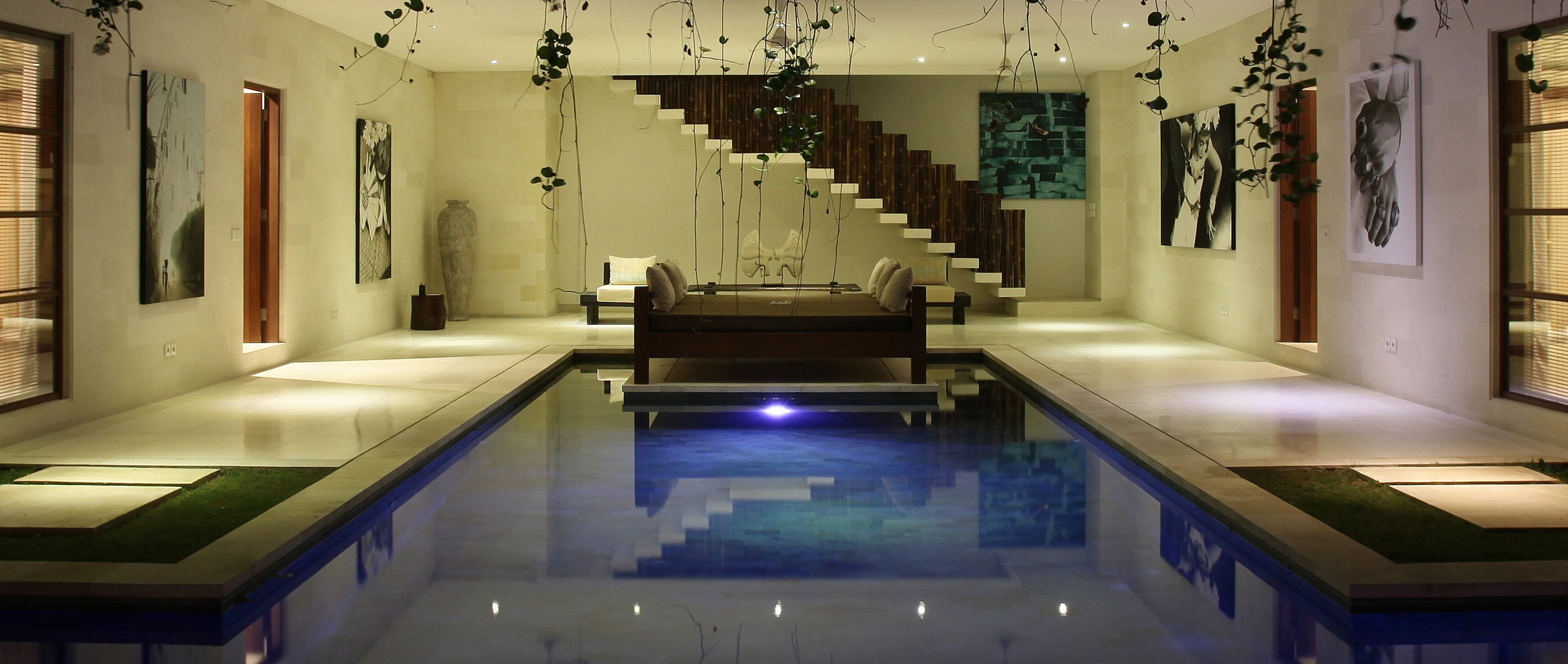 Un interior moderno con una piscina central, una escalera y obras de arte en las paredes.