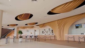 Un vestíbulo amplio con diseño moderno, que cuenta con una mesa de recepción, una escalera y una planta grande.