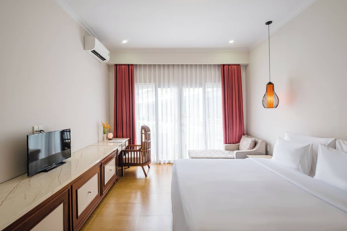 Una habitación de hotel con una cama, televisión, escritorio y silla.